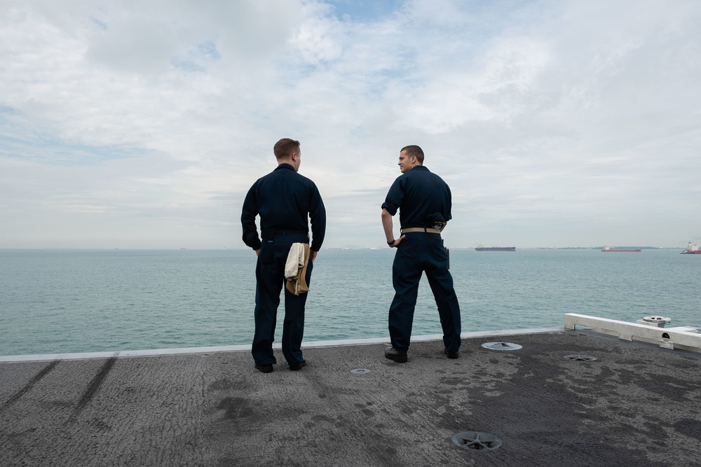 Sailors watch from the flight deck as the Nimitz-class aircraft carrier USS John C. Stennis (CVN 74) pulls in to Singapore.