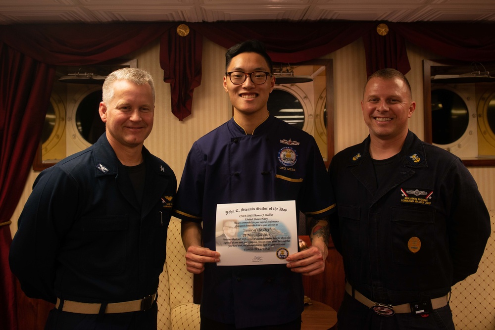 Culinary Specialist Seaman Apprentice Thomas Halbur, center, poses for a photograph as the Sailor of the Day with Capt. Randy Peck, left, commanding officer of USS John C. Stennis (CVN 74), and Command Master Chief Benjamin Rushing.