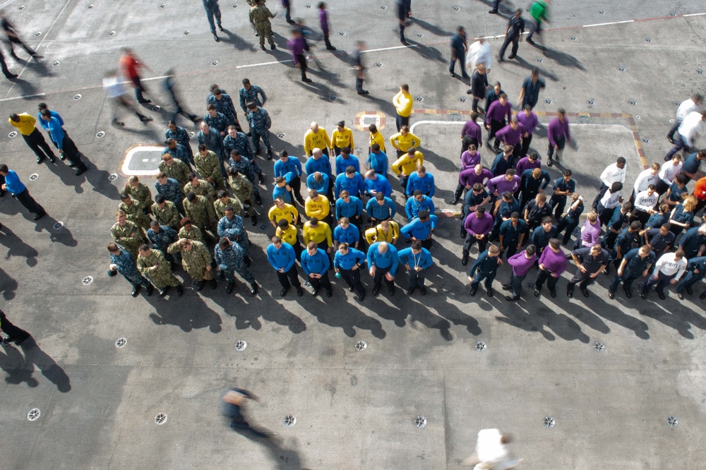 Sailors from the Air department aboard USS John C. Stennis gather into a formation before quarters on the flight deck.