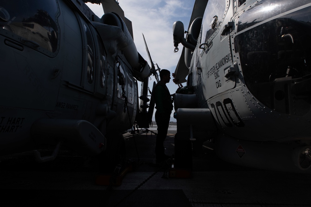 A Sailor conducts maintenance on an MH-60S Knight Hawk, with Helicopter Sea Combat Squadron (HSC) 14, on the flight deck aboard USS John C. Stennis (CVN 74).