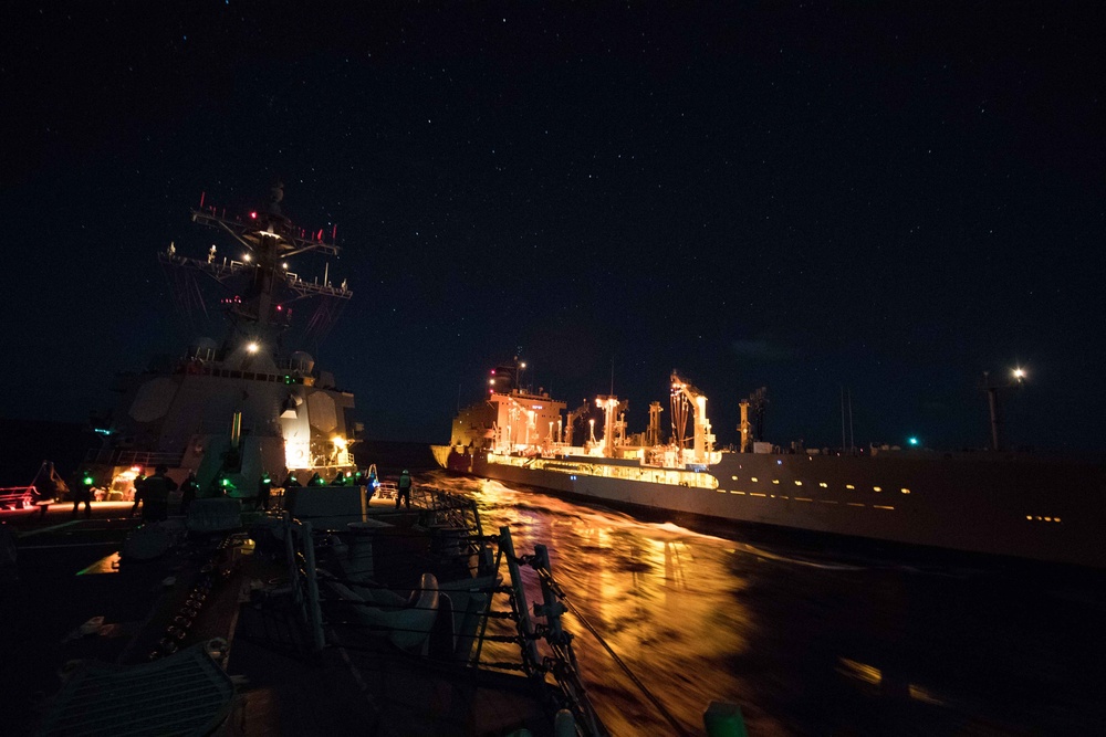 Sailors handle a line aboard USS Chung-Hoon (DDG 93), left, during a replenishment-at-sea.