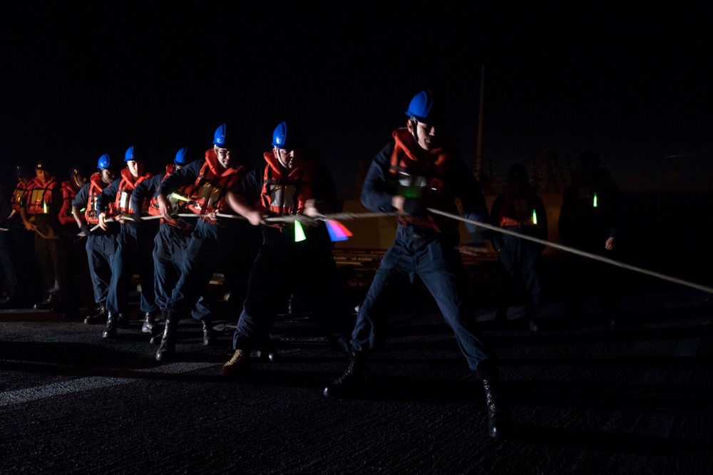 Sailors heave in line aboard USS Spruance (DDG 111) during a replenishment-at-sea.