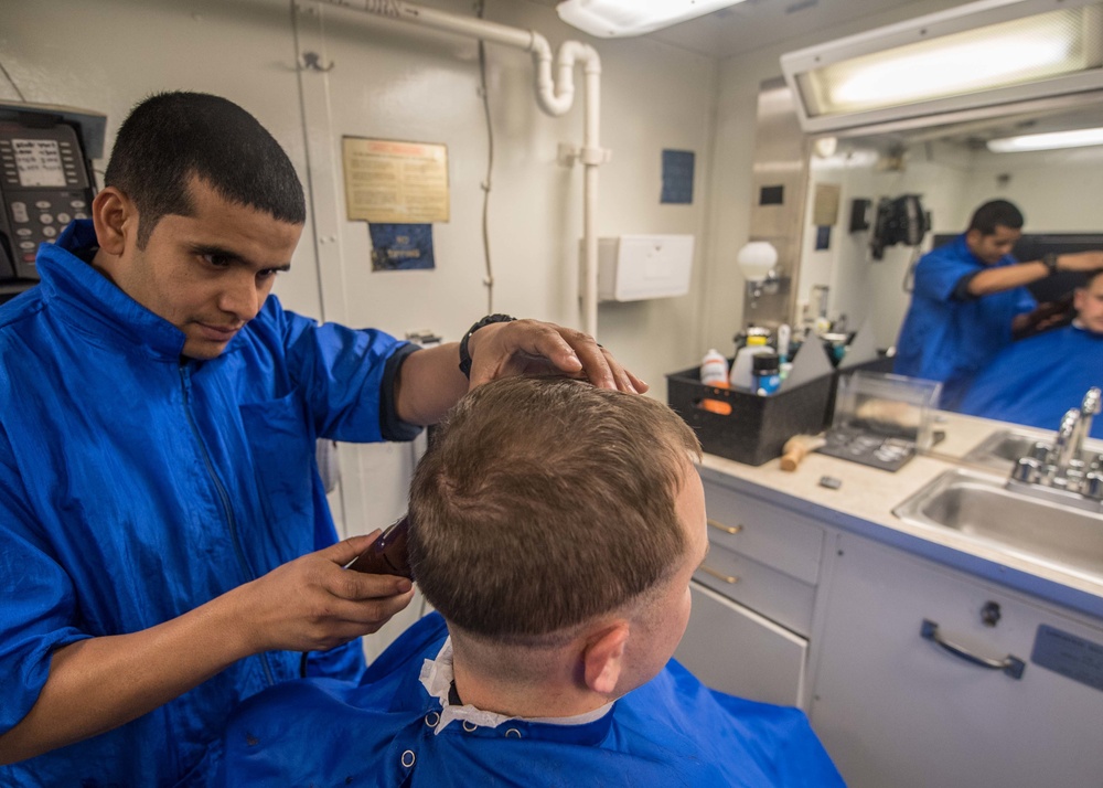 Ship's Serviceman 3rd Class Banod Panday gives a Sailor a haircut aboard USS Mobile Bay (CG 53).