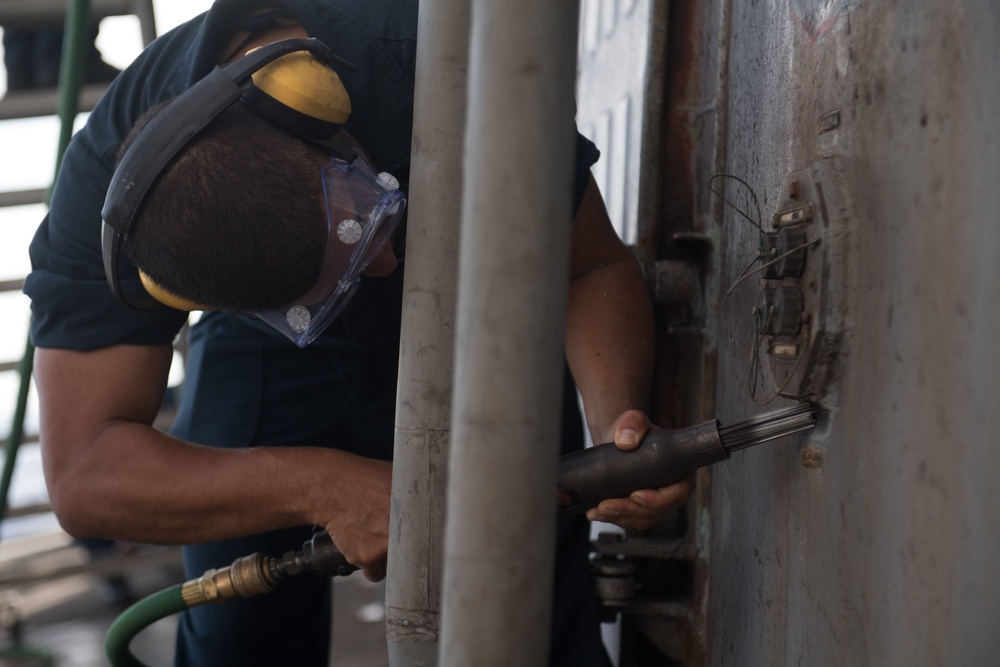 Seaman Joshua Asencio conducts preservation maintenance on the main deck of USS Chung-Hoon (DDG 93).