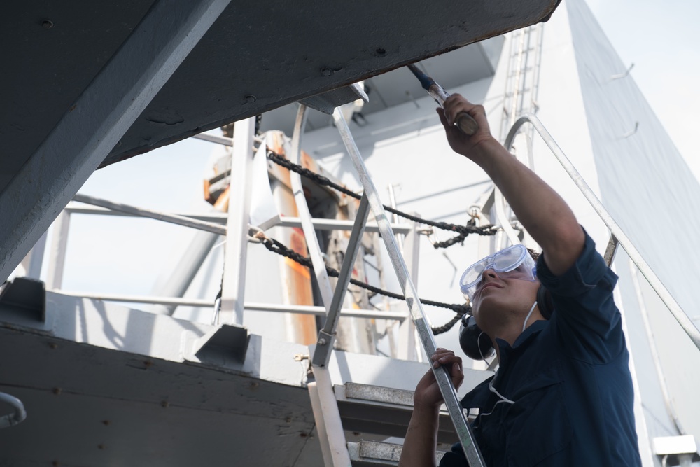 Seaman Emanule Martinez conducts preservation on the main deck of USS Chung-Hoon (DDG 93).