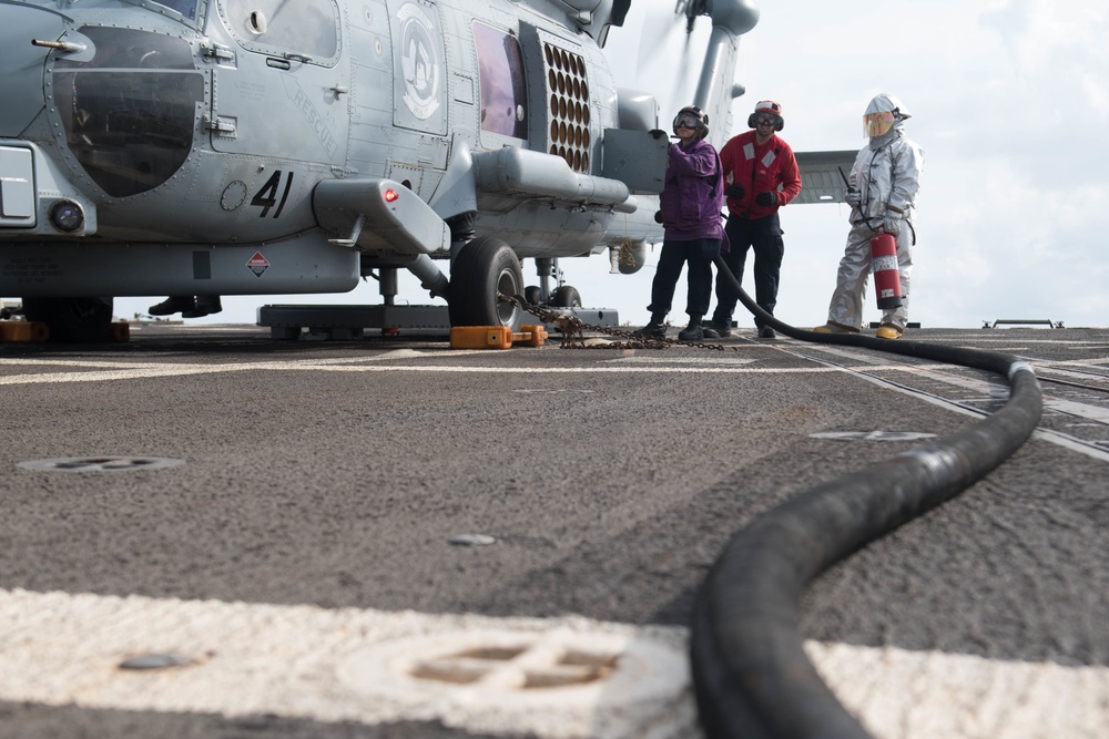 Sailors monitor a fuel line while refueling an MH-60R Sea Hawk, with Helicopter Maritime Strike Squadron (HSM) 37, aboard USS Chung-Hoon (DDG 93).