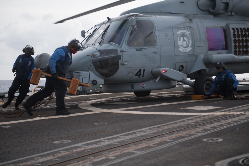 Sailors remove chocks and chains from an MH-60R Sea Hawk, with Helicopter Maritime Strike Squadron (HSM) 37, aboard USS Chung-Hoon (DDG 93).