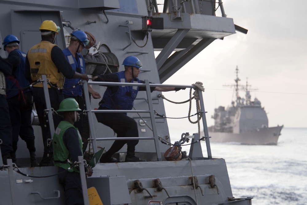 Boatswain’s Mate Seaman Aaron Tierney right, heaves in a shot line aboard USS Spruance (DDG 111) to begin rigging for a replenishment-at-sea.