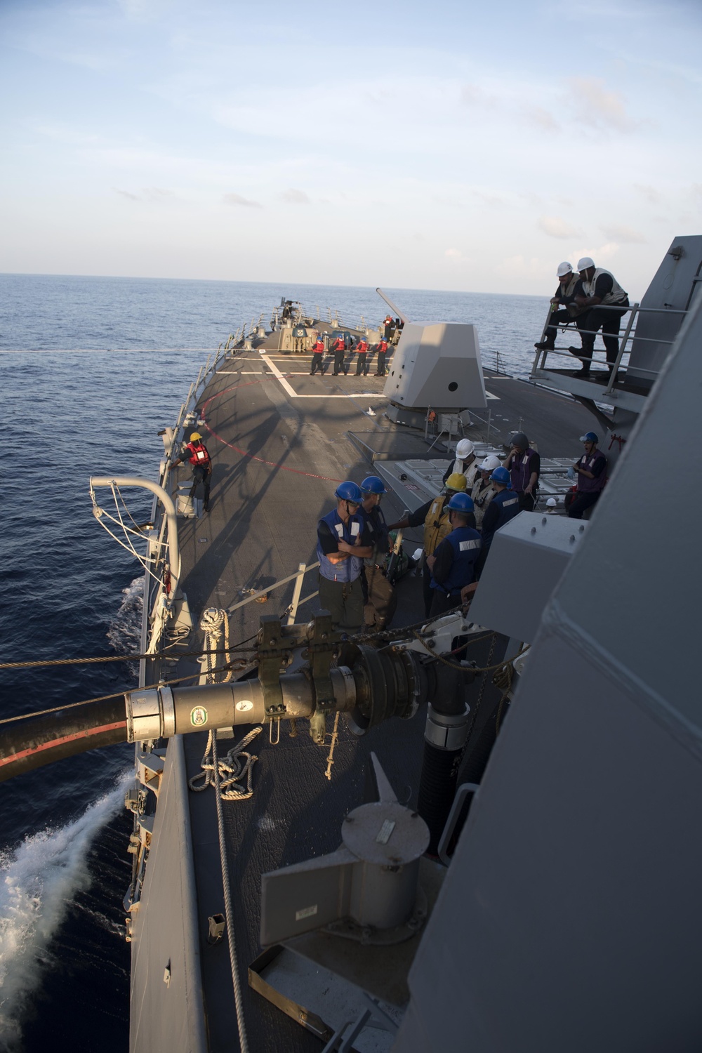 Sailors aboard USS Spruance (DDG 111) man their stations while receiving fuel from USNS Charles Drew (T-AKE 10) during a replenishment-at-sea.
