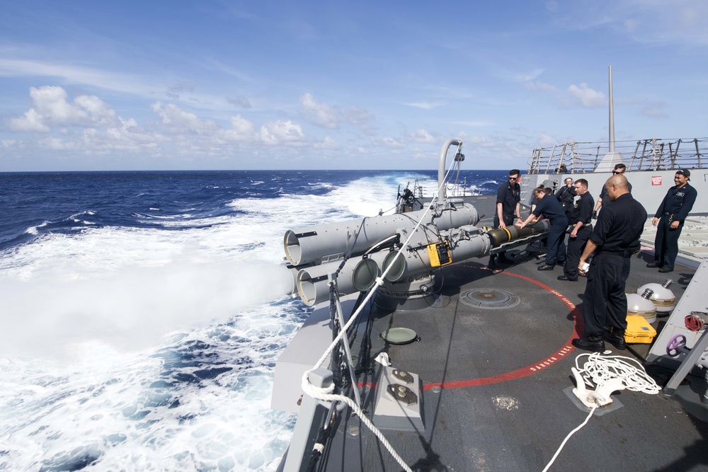 Sailors maintain positive control of a MK 46 Mod 5A(S) torpedo as an air slug is fired during maintenance on the launch system aboard USS Spruance (DDG 111).