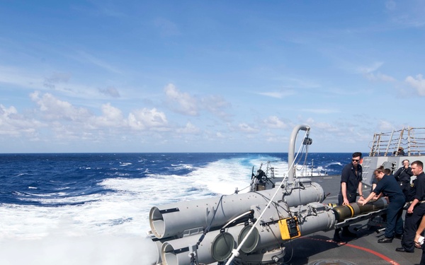 Sailors maintain positive control of a MK 46 Mod 5A(S) torpedo as an air slug is fired during maintenance on the launch system aboard USS Spruance (DDG 111).