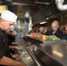 Command Master Chief Chad Schultz, left, the command master chief of USS Chung-Hoon (DDG 93), serves food to Sailors in the galley for Thanksgiving dinner.