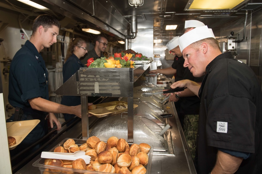 Cmdr. Brent Jackson, right, the commanding officer of USS Chung-Hoon (DDG 93), serves food to Sailors in the ship’s galley for the Thanksgiving dinner.