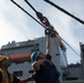 Seaman Matthew Plucinski, right, attaches a pelican hook to the sliding padeye aboard USS Chung-Hoon (DDG 93).