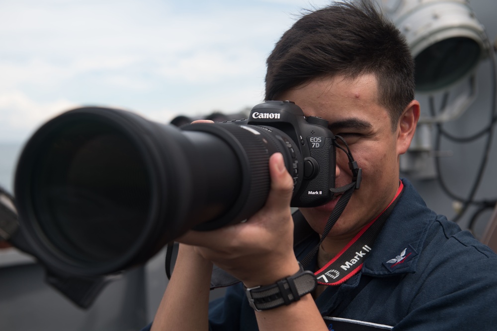Information System Technician 3rd Class Zachary Cervantez uses a camera to collect information aboard USS Chung-Hoon (DDG 93).