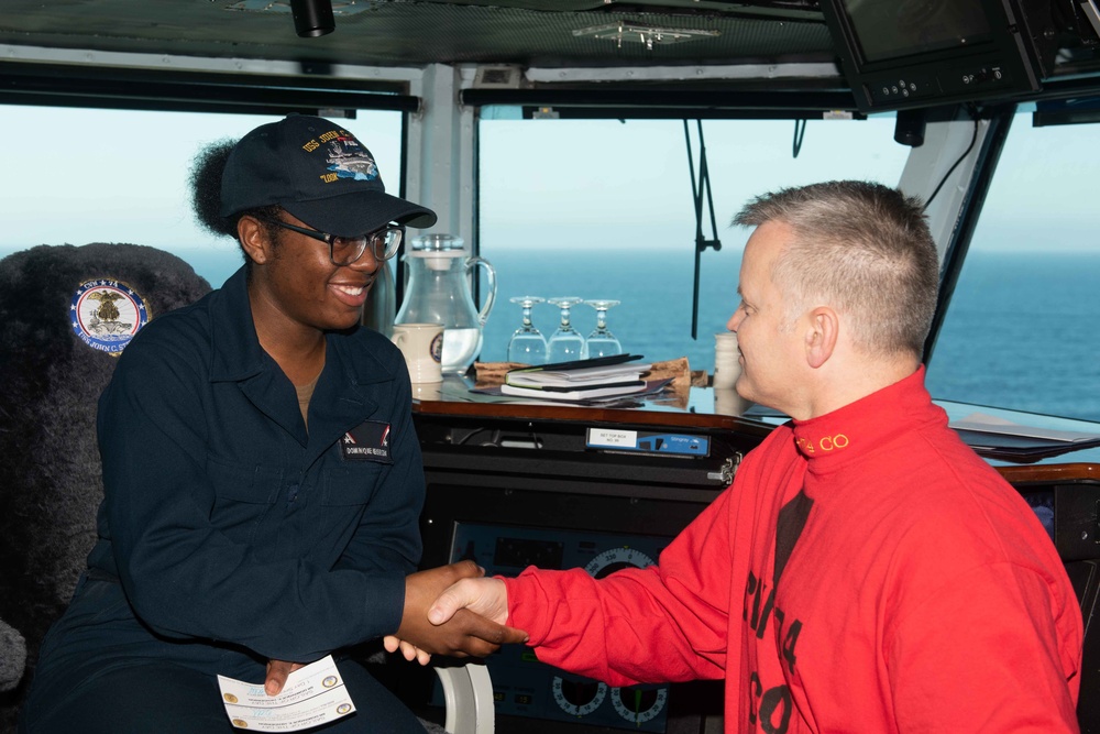 Seaman Recruit Dominique E. Henderson receives a challenge coin from Capt. Randy Peck, commanding officer of USS John C. Stennis (CVN 74), for her selection as the Sailor of the Day.
