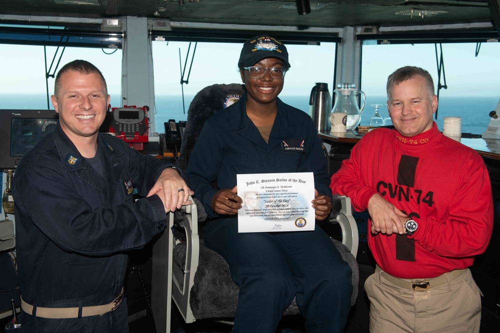 Seaman Recruit Dominique E. Henderson poses for a photograph as the Sailor of the Day with Capt. Randy Peck, right, commanding officer of USS John C. Stennis (CVN 74), and Command Master Chief Benjamin Rushing.