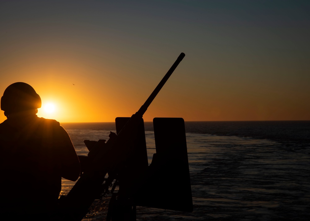 Aviation Ordnanceman 3rd Class Brandon Ellington searches the horizon for an inflatable naval gunnery target during a crew-served weapons fire on the fantail aboard USS John C. Stennis (CVN 74).