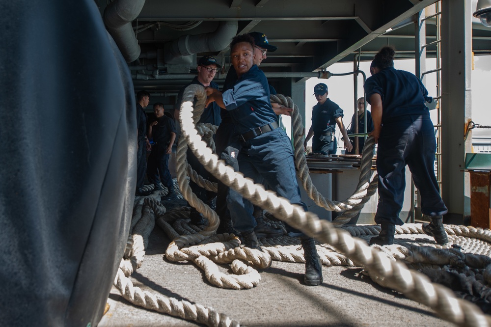 Boatswain’s Mate 3rd Class Donye Wright, from Virginia Beach, Virginia, handles mooring line on the fantail aboard the Nimitz-class aircraft carrier USS John C. Stennis (CVN 74) as the ship gets underway from Changi Naval Base following a scheduled port