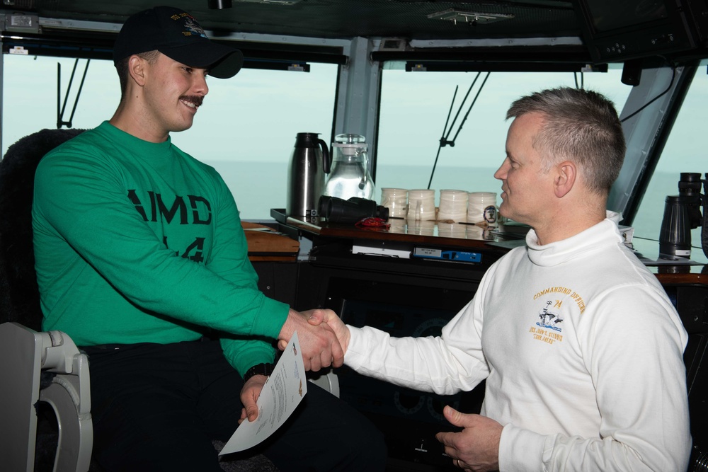 Aviation Support Equipment Technician 3rd Class Garrett Rains receives a Commanding Officer’s coin as the Sailor of the Day, from Commanding Officer Capt. Randy Peck, aboard USS John C. Stennis (CVN 74).