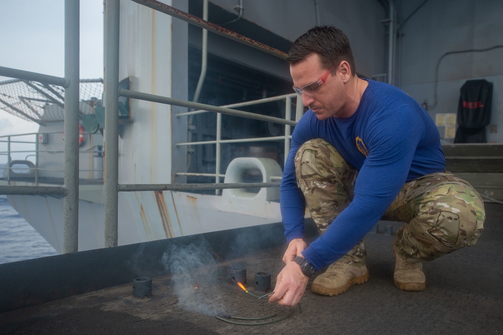 Chief Explosive Ordnance Disposal Technician Isaac Russell ignites detonation fuses during a training exercise on the fantail aboard USS John C. Stennis (CVN 74).