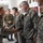 Maryland Guard, Bosnia-Herzegovina armed forces celebrate 15-year partnership A civilian woman is greeting and shaking hands with military personnel in a hallway or corridor of what appears to be a military facility. The soldiers are wearing woodland MARPAT (digital camouflage) uniforms consistent with U.S. Marines or allied forces. The wall behind them displays various military plaques, crests, and unit insignia.