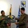 Maryland Guard, Bosnia-Herzegovina armed forces celebrate 15-year partnership Two military officers, one in US Army camouflage uniform and one in an olive dress uniform, are jointly holding a commemorative plaque marking '15 Years Continued Cooperation, Support, & Friendship Est. 2003'. The setting appears to be an official military meeting room with flags from the United States, Maryland, Bosnia and Herzegovina, and a framed coat of arms on the wall. The occasion appears to be a bilateral military partnership anniversary ceremony.