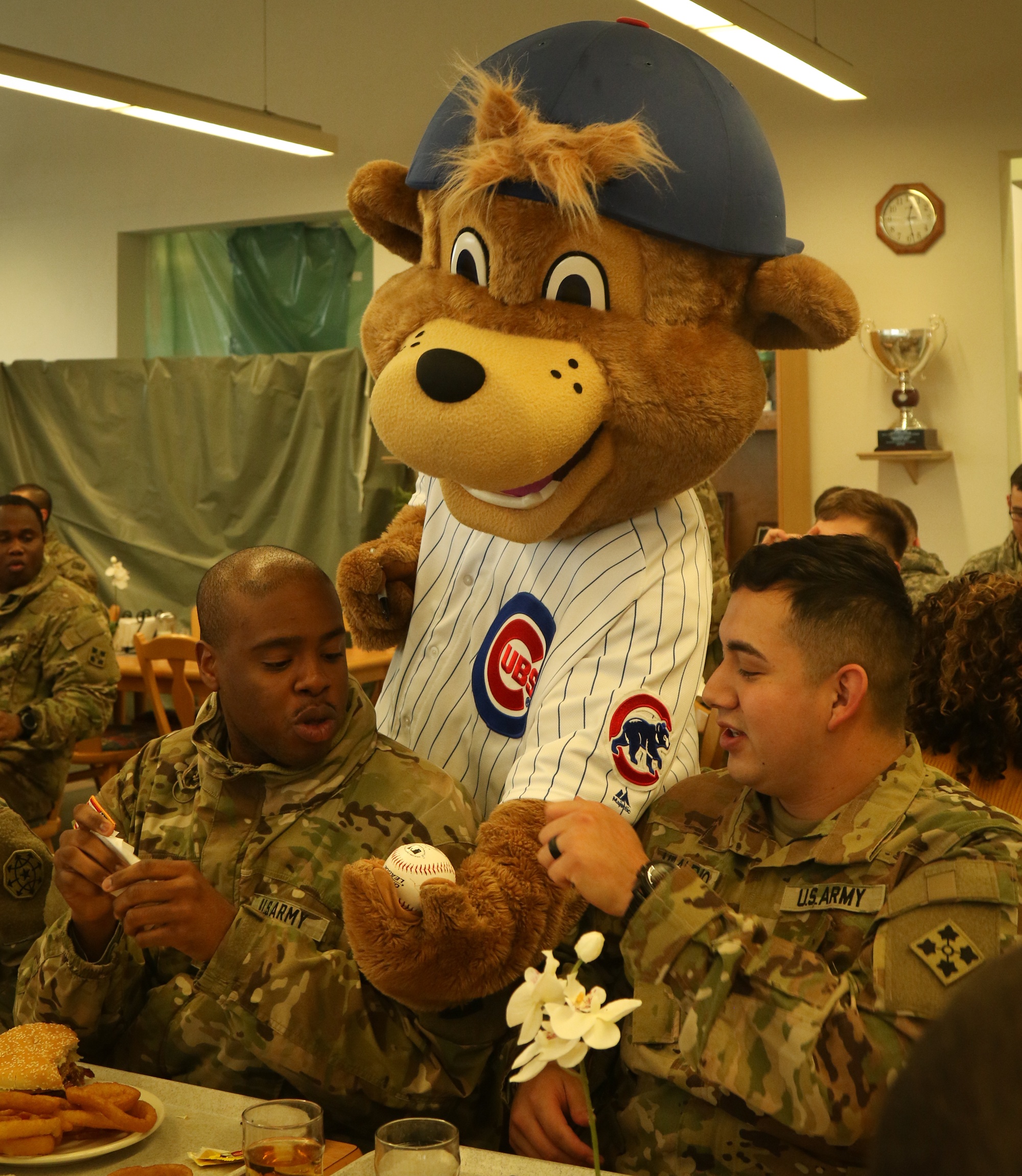 A U.S. Army Soldier's son poses with Clark, the Chicago Cubs mascot, at the  USO at USAG Bavaria in Grafenwoehr, Germany, Dec. 11, 2018. The USO  sponsored a Chicago Cubs mascot tour