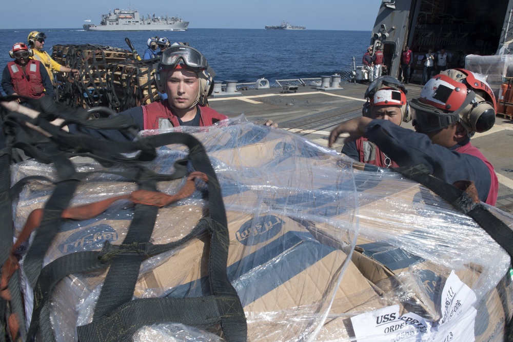 U.S. Navy Sailors remove a cargo net from supplies on the flight deck of the guided-missile destroyer USS Spruance (DDG 111)