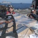 U.S. Navy Sailors remove a cargo net from supplies on the flight deck of the guided-missile destroyer USS Spruance (DDG 111)