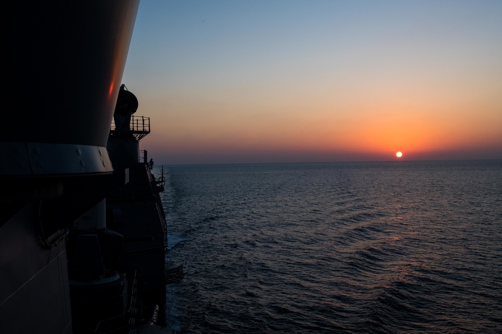 The guided-missile cruiser USS Mobile Bay (CG 53) transits towards a setting sun in the Indian Ocean