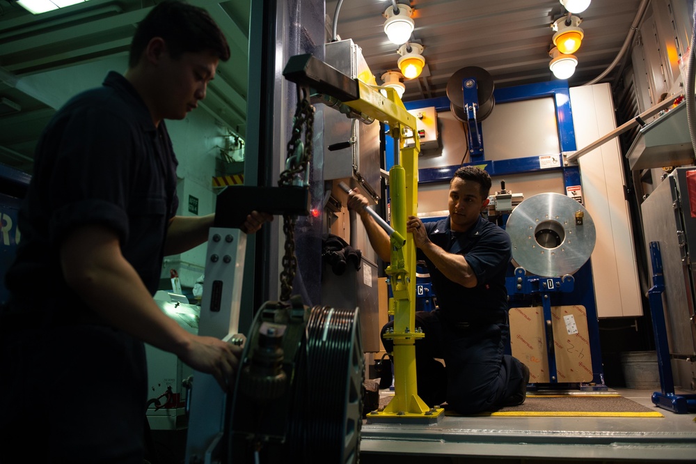 Sailors re-wrap cable reel in the hangar bay of USS John C. Stennis (CVN 74)