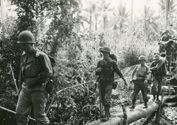 32nd Division Soldiers cross a rudimentary log bridge in the South Pacific in 1942 during World War II