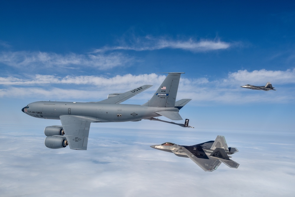Two U.S. Air Force F-22 Raptors fly next to a KC-135 Stratotanker