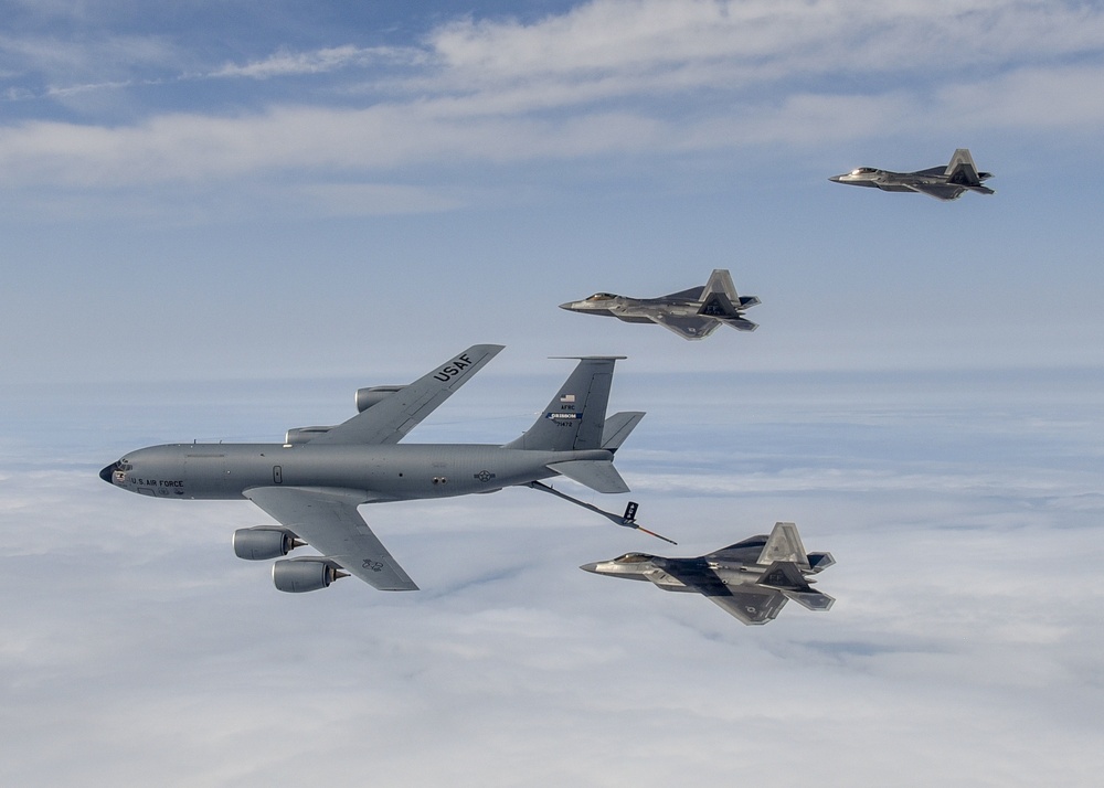 KC-135 Stratotanker and F-22 Raptors prepare to conduct aerial refueling