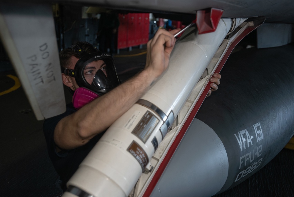 U.S. Sailor paints an F/A-18E Super Hornet aboard the aircraft carrier USS John C. Stennis (CVN 74)