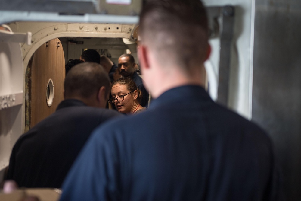 U.S. Navy Sailors transport food and supplies aboard the guided-missile cruiser USS Mobile Bay