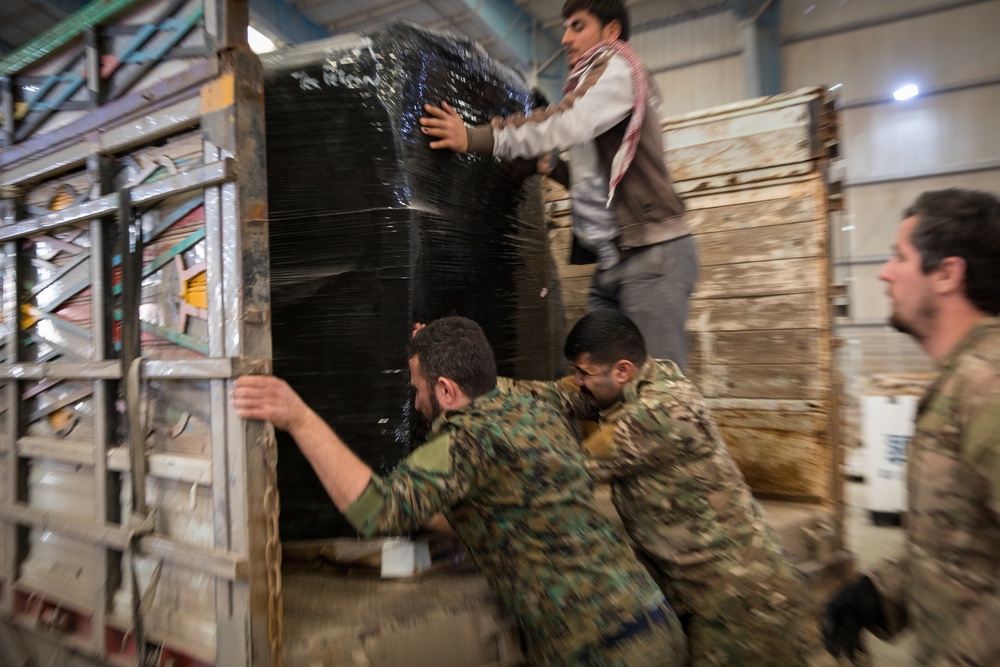Coalition Forces members distribute pallets of medical supplies to SDF, local doctors