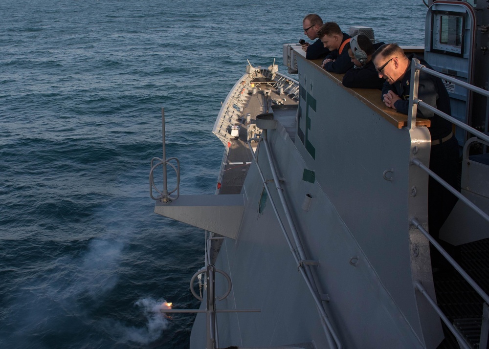 U.S. Sailors observe a flare during a man overboard drill