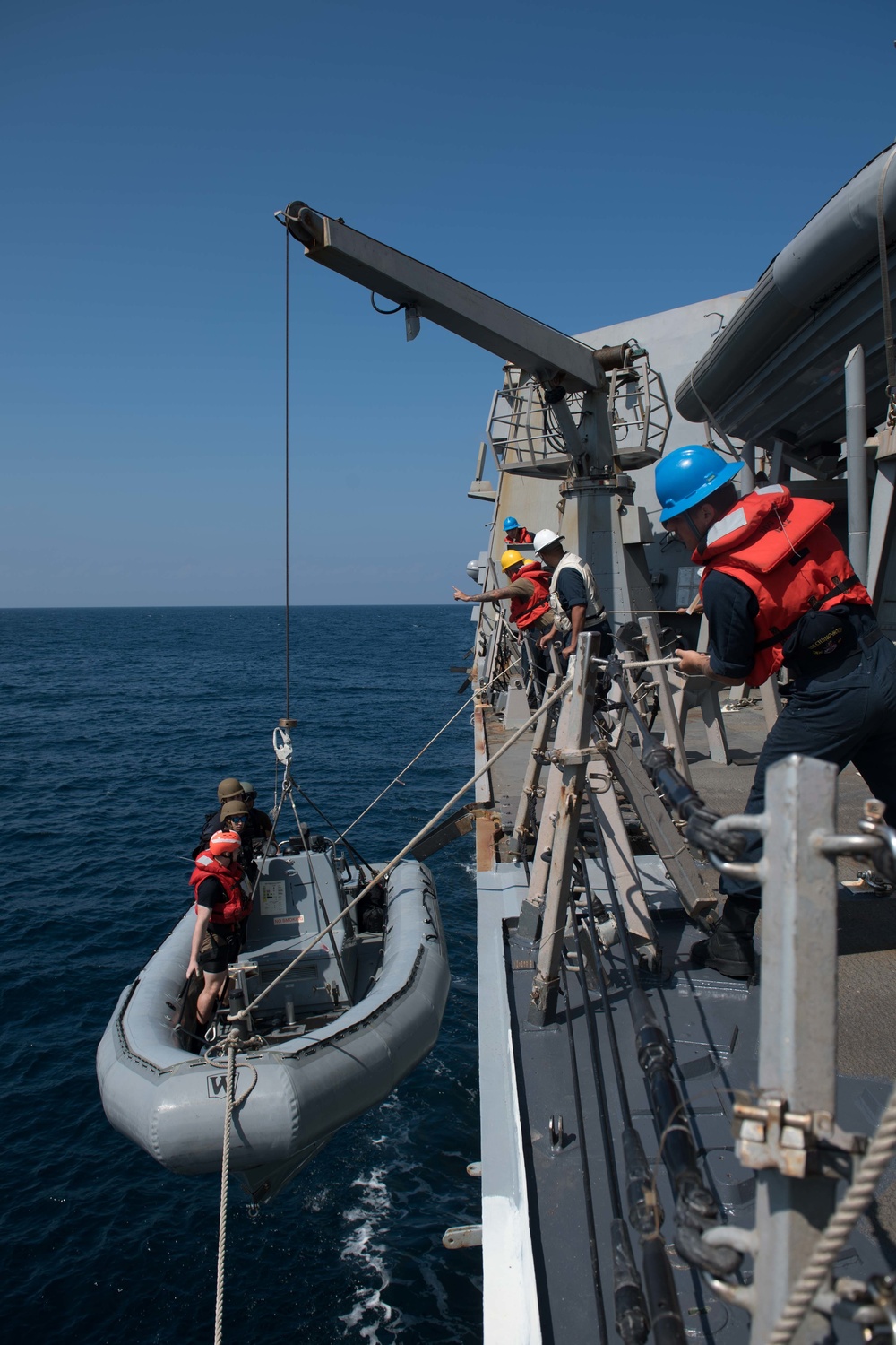 U.S. Sailors handle lines to raise a rigid-hull inflatable boat onto USS Chung-Hoon (DDG 93) in the Gulf of Aden