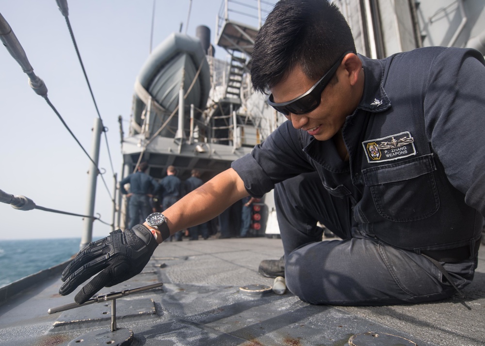 U.S. Navy Gunner's Mate 3rd Class Daniel Zhang, from Houston, tightens a bolt aboard USS Mobile Bay