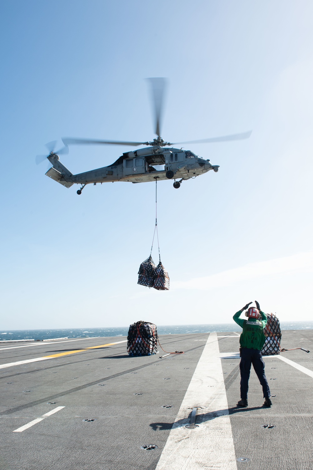 U.S. Sailor directs an MH-60S Knight Hawk