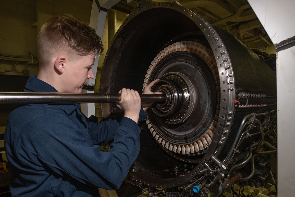 U.S. Sailor conducts maintenance on a jet engine