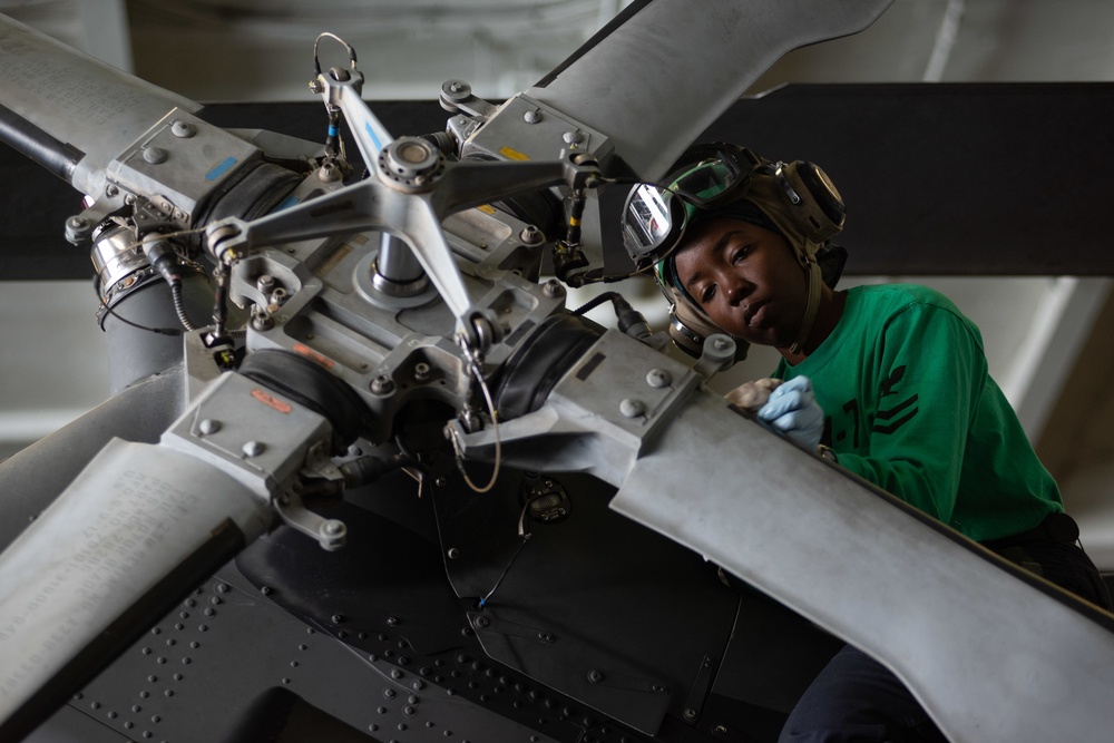 U.S. Sailor cleans paddles of an MH-60R Sea Hawk