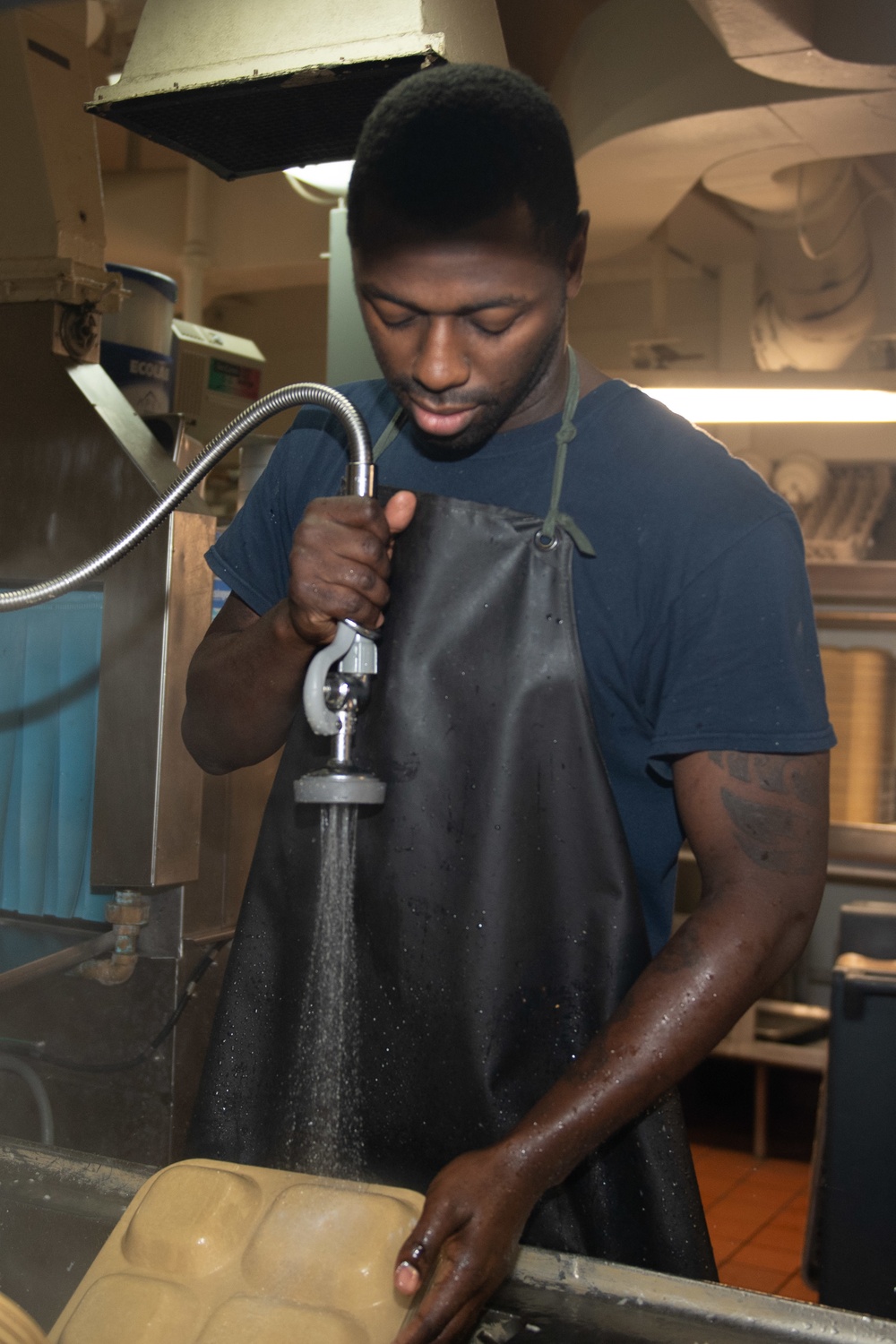 U.S. Sailor cleans trays in scullery