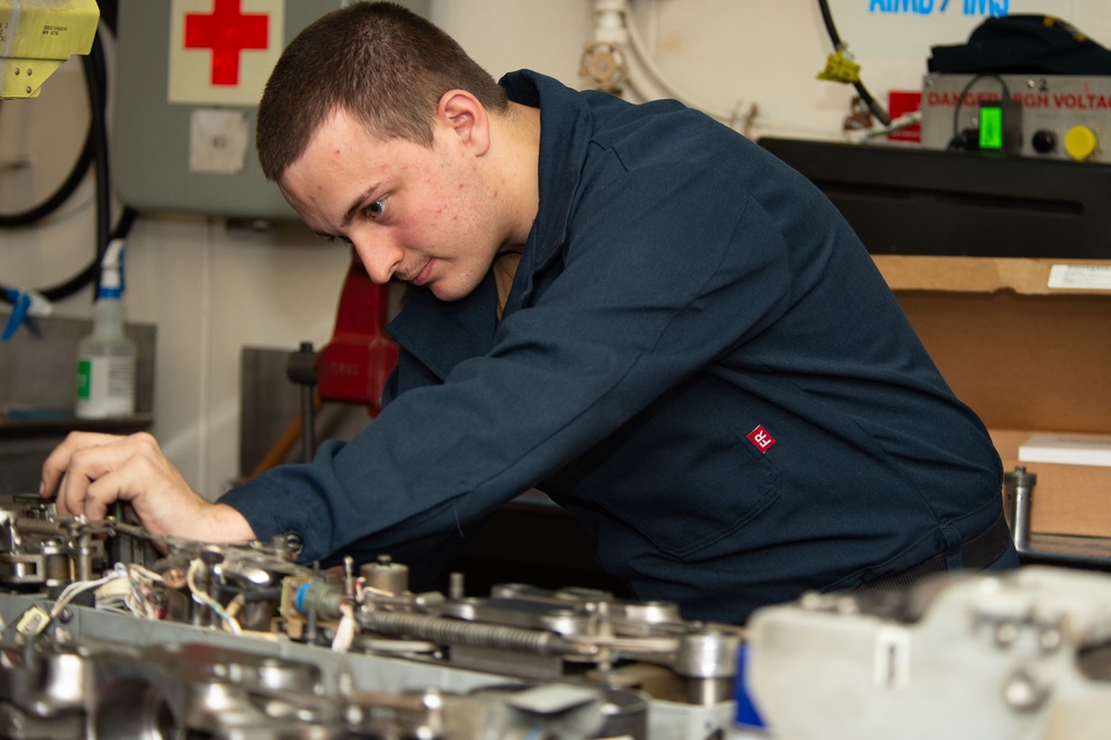 U.S. Sailor performs inspection on a bomb rack unit