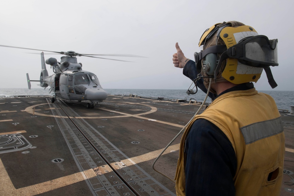 U.S. Navy Boatswain’s Mate 3rd Class Brandon Ross, from Honeapath, South Carolina, signals to the pilot of a Panther anti-submarine helicopter