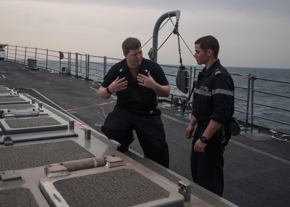 U.S. Navy Gunner's Mate 1st Class Dustin Smillie, from Prescott, Arkansas, left, explains the functions of a vertical launch system to French Marine Nationale Second-maître Martin, aboard USS Mobile Bay (CG 53)