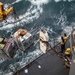 U.S. Sailors aboard the guided-missile cruiser USS Mobile Bay (CG 53), receive pallets of food during a replenishment-at-sea