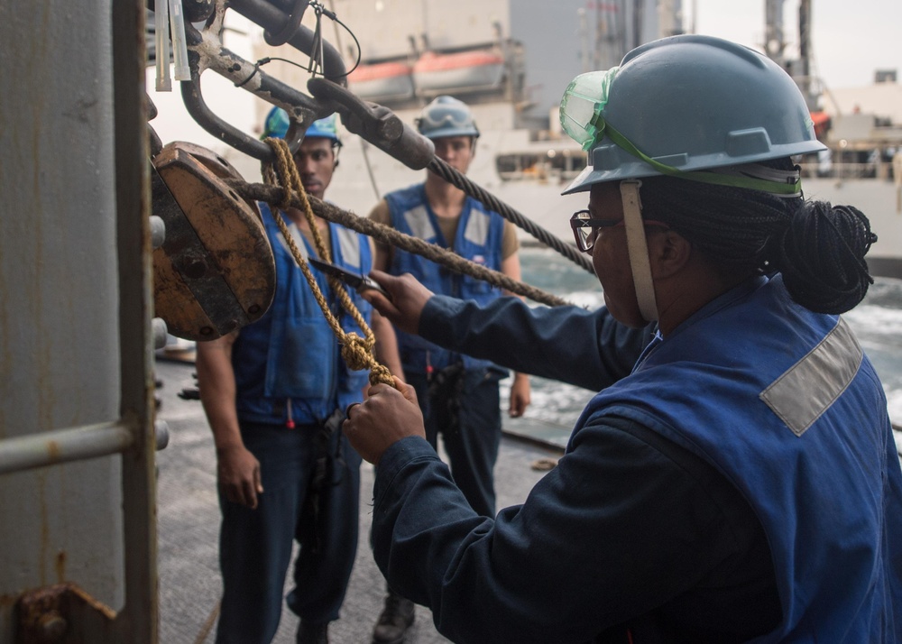 U.S. Navy Seaman Danye Garrett, from Madison, Illinois, cuts a line during a replenishment-at-sea with the fleet replenishment oiler USNS Guadalupe